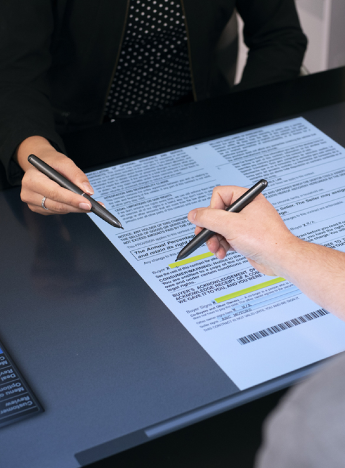 Two hands holding electronic pens above a docuPAD electronic form